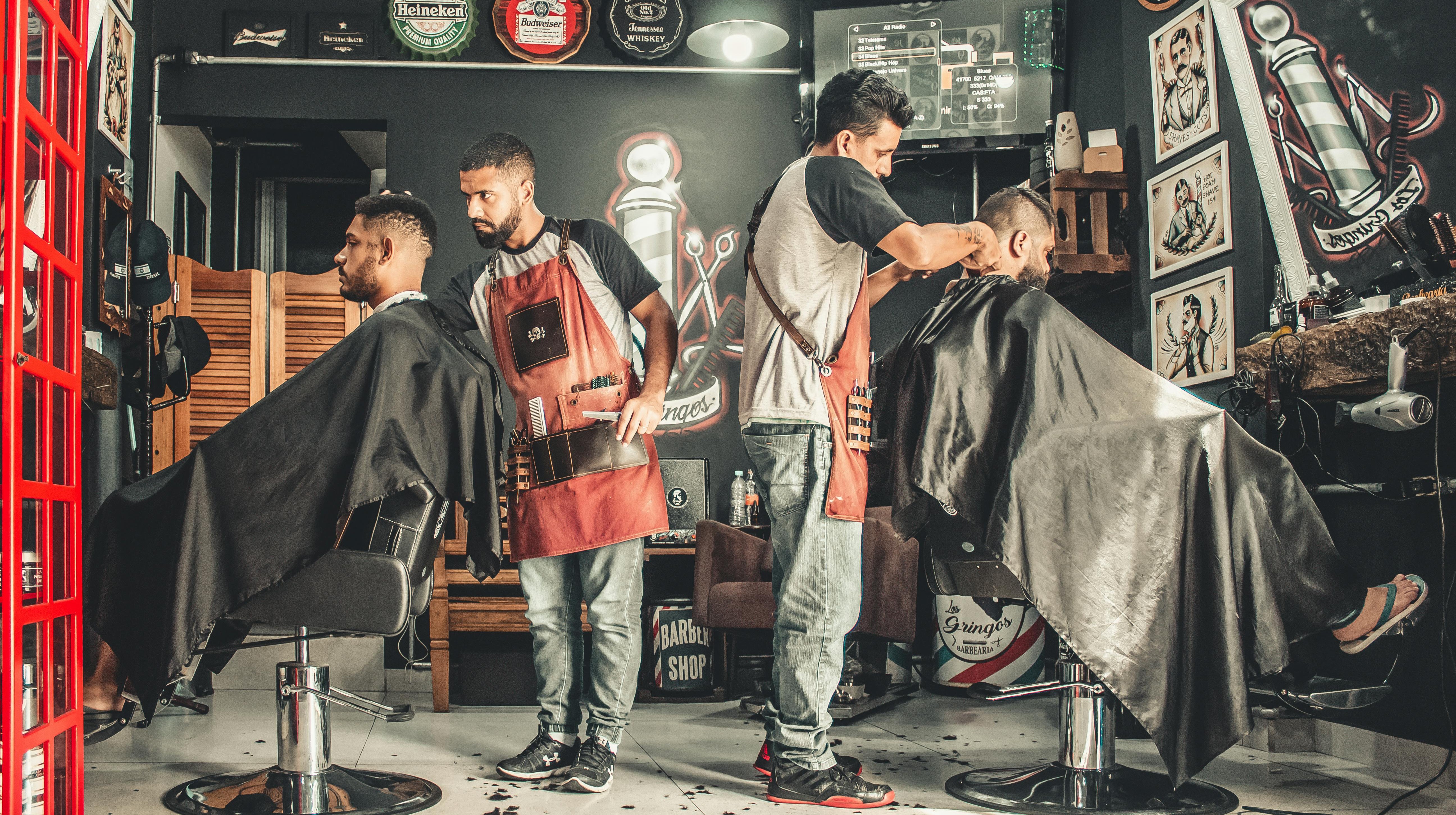Two barbers cutting hair of two clients in the GoodFellas barber shop